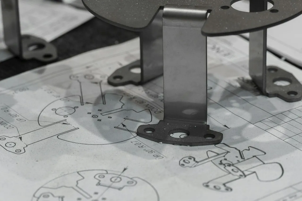 Manufactured metal components resting on engineering blueprints